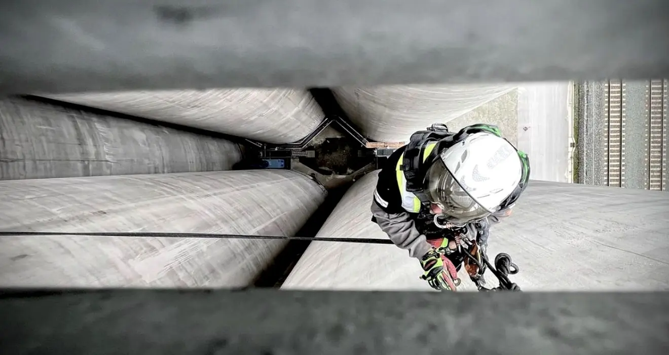 Rope access technician descending between industrial silos