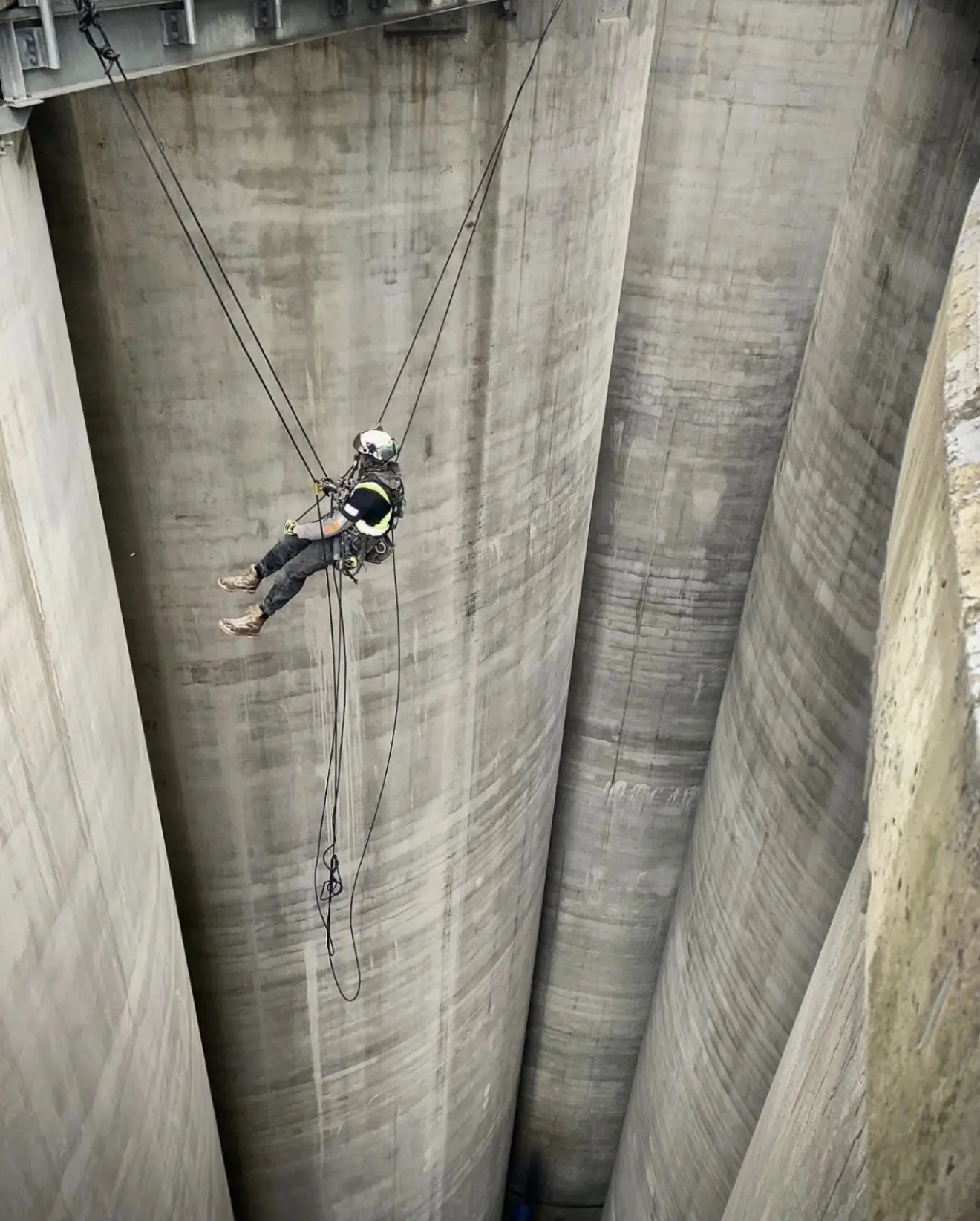 Rope technician suspended between concrete silos