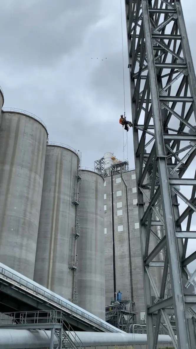 Industrial rope access technician working above a facility
