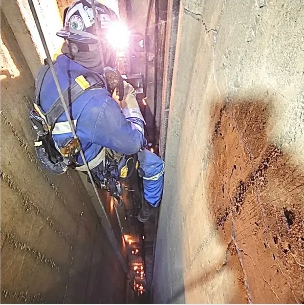 Rope access welder working in a confined industrial structure
